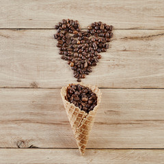 Heart shape make by roasted coffee been from waffle cone on wooden background