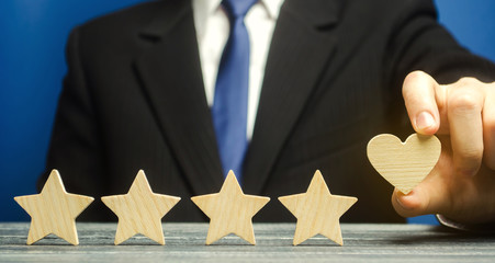 A man points to a heart instead of a fifth star. Loyalty and customer choice. The evaluation of visitors. Quality level, good service. Best customer rating. Feedback. Rating of hotels and restaurants.