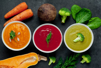 Obraz na płótnie Canvas Set of vegetable soups. Broccoli, spinach, green peas soup. Pumpkin and carrot soup. Beetroot and carrot soup on a stone background.