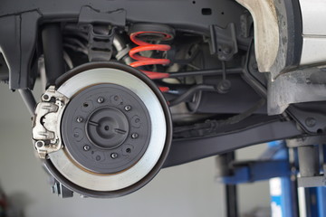 Disc brake of the vehicle for repair, in process of new tire replacement.  Car brake repairing in garage.Selective focus disc brake on car, in process of new tire replacement.Close up.
