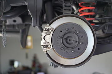 Brake disk and detail of a wheel hub. Disc brake of the vehicle for repair, in process of new tire replacement. Car brake repairing in garage.Close up.