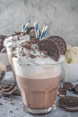 Coffee mocha milkshake with cookies and cream. Ice cream and chocolate cookies sweet latte cocktail. On gray concrete table, with spoon and cup of vanilla ice cream. Copy space