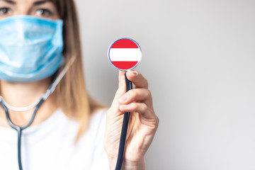 female doctor holding a stethoscope on a light background. Added flag of Austria. Concept medicine,...