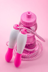 Jump rope and bottle of water on pink background