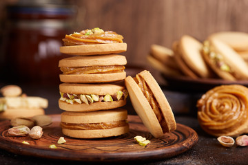 Delicious homemade alfajores cookies with milk caramel cream filling, decorated with pistachio nuts. Sandwich cookies. 