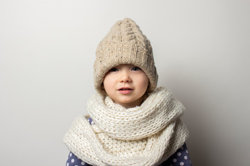 beautiful little baby in a hat on a light background. Concept of children's emotions, winter, shopping