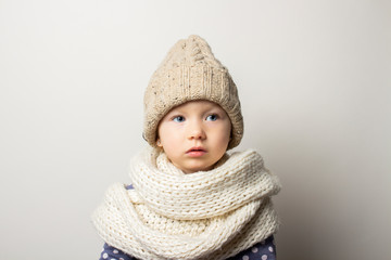 beautiful little baby in a hat on a light background. Concept of children's emotions, winter, shopping