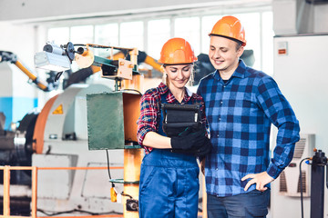 Male and Female Industrial Worker in Hard Hats looks in industrial controller.They Work in a Heavy Industry Manufacturing Factory.