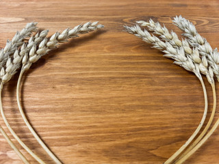Stalks of wheat lie on a wooden table.