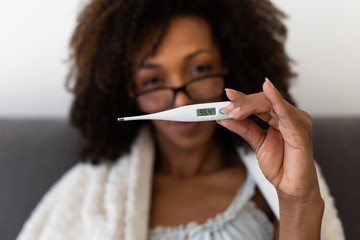 Woman shows a thermometer with normal body temperature after overcoming a virus infection and...