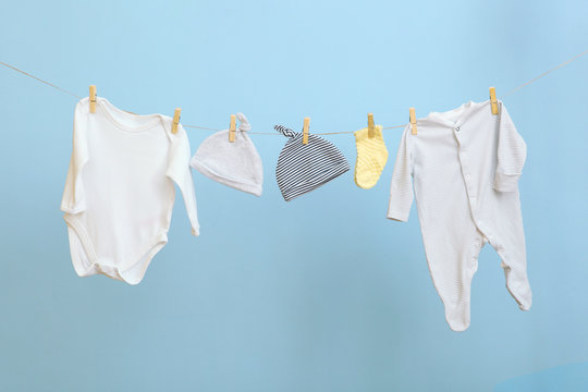 Baby clothes on a rope on a colored background. The concept of washing baby clothes.