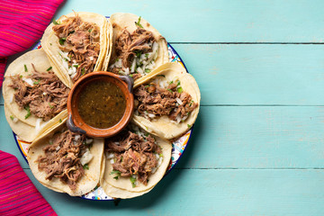 Mexican slow cooked lamb tacos also called barbacoa on turquoise background