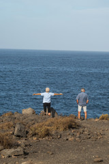 Fototapeta na wymiar An elderly couple a man and a woman on a rocky shore near the ocean play sports to improve their health. Healthy lifestyle of old people.