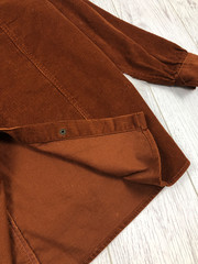 Detail of a brown corduroy shirt close-up on a wooden background