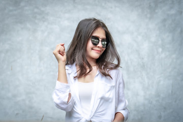 Asian beautiful woman with yellow skin, long black hair, wearing a white shirt, jeans showing her emotions.  Cement wall background-01