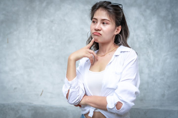 Asian beautiful woman with yellow skin, long black hair, wearing a white shirt, jeans showing her emotions.  Cement wall background-01