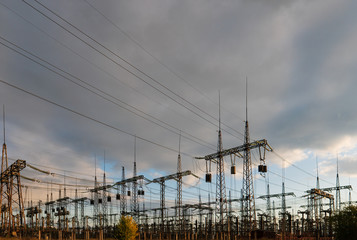 distribution electric substation with power lines and transformers, at sunset.