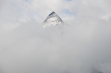 Mountain summit rising up through heavy clouds. Summertime in the Grossglockner mountain alps