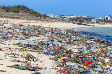 Closeup plastic trash on the sandy beach of a tropical sea