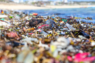 Closeup plastic trash on the sandy beach of a tropical sea