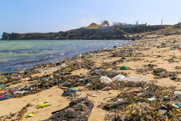 A view along a sandy beach full of plastic garbage.