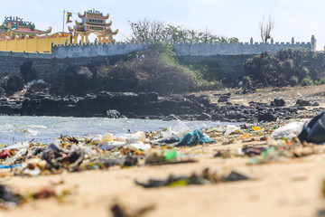 Buddhist temple by the tropical sea and a sandy beach full of plastic litter