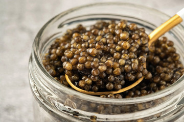 black caviar in a glass jar, gray background, close-up