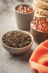 black and red caviar in bowls, snacks on a gray concrete background