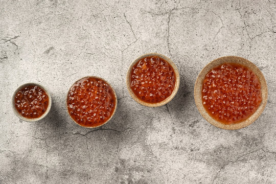 red caviar in bowls on a gray concrete background, copy space, top view