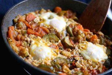 Shakshuka in a pan, with seasonal vegetables and eggs. Selective focus.