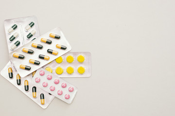 Heap of medical pills in yellow, pink and green colors. Pills in plastic package.