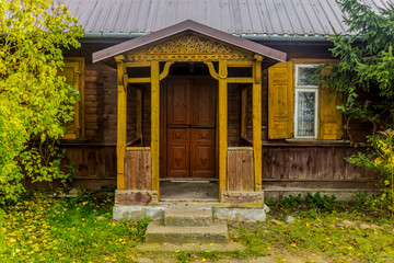 Late fall . The wooden porch of an old rustic wooden house. Wooden siding, wooden patterns, metal roof. Podlasie, Poland.