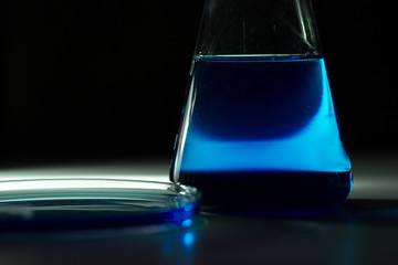 Petri dishand and retort blue chemical reagent. Chemical experiment with Laboratory glass