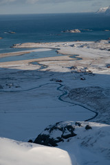 Amazing  winter landscape of Lofoten Islands. Picture taken while hiking to famous Kvalvika beach. View to a coast line surrounded by mountains, river meander and small village. Touristic area. 
