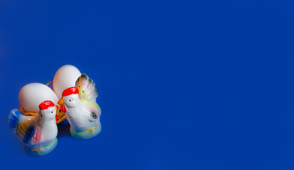 beautiful easter decoration with Figure of a rooster, hen and eggs in a basket on a blue background. Copy space.