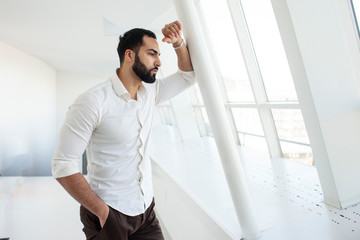 Fototapeta premium handsome successful guy in the morning puts on a white shirt at home near the window