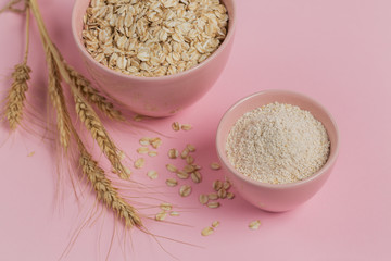 Bowl of dry oat flakes with oatmeal and ears of wheat on light background. Healthy skin, facial and body care.