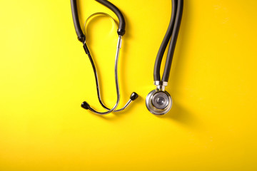 Medical stethoscope on a yellow background, top view