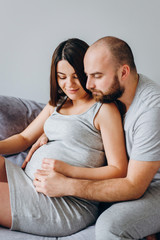 Pregnancy. Young couple waiting for baby. Wonderful expectant parents cuddle in their apartment awaiting birth
