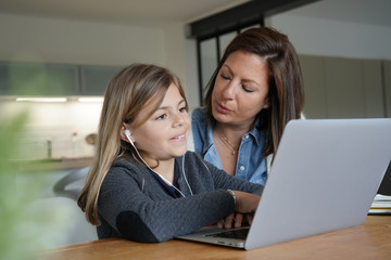 Mother and kid at home doing homework online