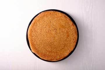 Plate with pancakes on a light wooden table, top view