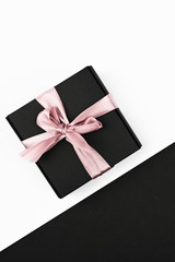 Black-white gifts. Colored ribbon wound on a black gift box. sleek layout, top view.