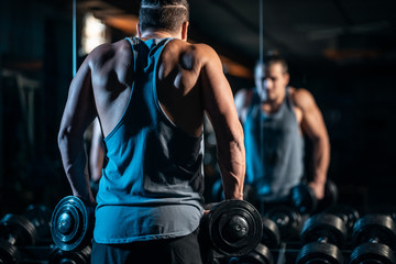 Fototapeta na wymiar young athlete has physical workout with dumbbell in modern gym