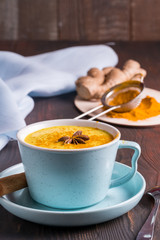 Golden  latte milk made tea with turmeric and spices on wooden background.