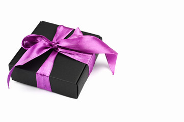 Gift black packaging with a purple bow on a white background. Cut out the background.