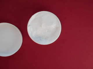 Natural cosmetic cream skincare product wellness and relaxation makeup mask on red background.