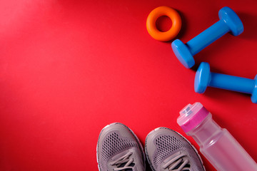 Water bottle, dumbbells, sneakers, sports symbols on a red background