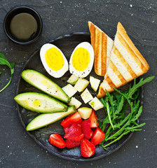 Breakfast and healthy snack of eggs, avocado, cheese and strawberries.