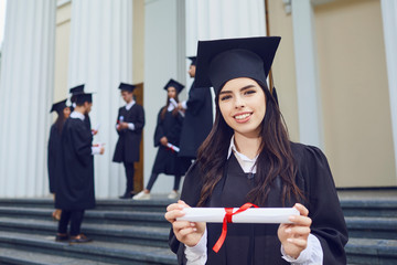 A girl graduate against the background of university graduates.