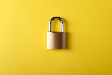 Small metal padlock on a yellow background
